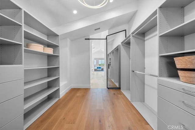 walk in closet with light hardwood / wood-style flooring