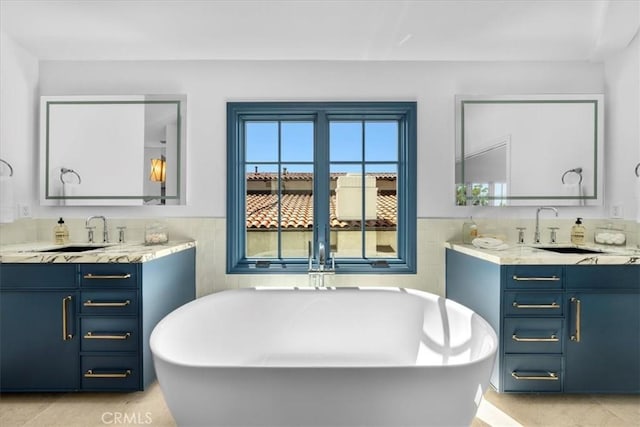 bathroom with a bathing tub, tile walls, vanity, and tile patterned floors