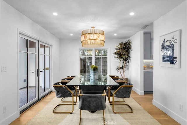 dining space featuring a notable chandelier, light hardwood / wood-style floors, and french doors