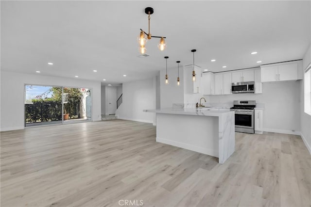 kitchen featuring white cabinetry, light hardwood / wood-style floors, appliances with stainless steel finishes, decorative light fixtures, and a chandelier