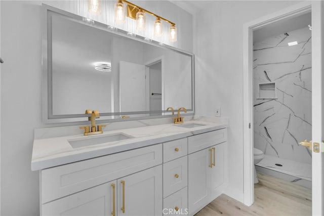 bathroom featuring hardwood / wood-style flooring, tiled shower, vanity, and toilet