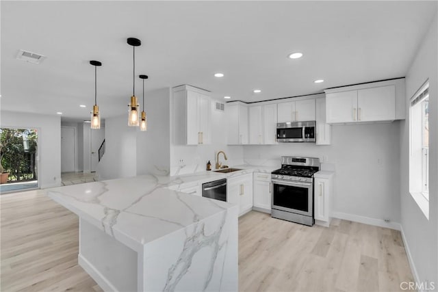 kitchen with light stone countertops, stainless steel appliances, white cabinets, and decorative light fixtures