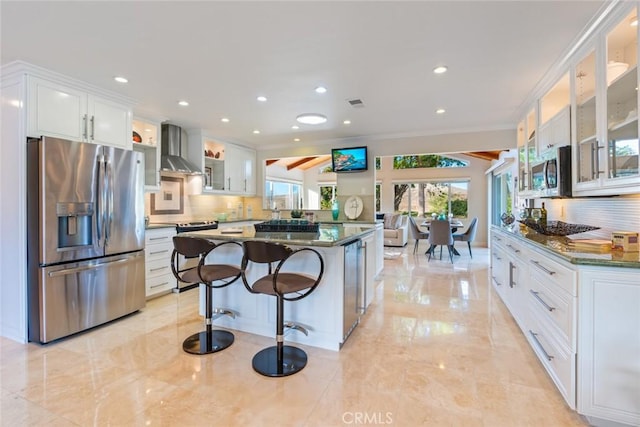 kitchen with stainless steel appliances, wall chimney exhaust hood, and white cabinetry