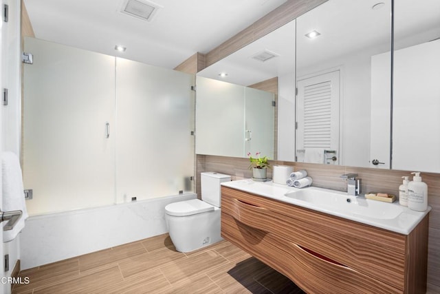 full bathroom featuring toilet, combined bath / shower with glass door, and vanity