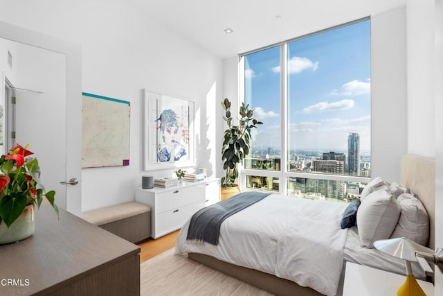 bedroom with floor to ceiling windows and light hardwood / wood-style flooring