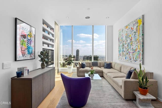 living room with light wood-type flooring, built in features, and floor to ceiling windows