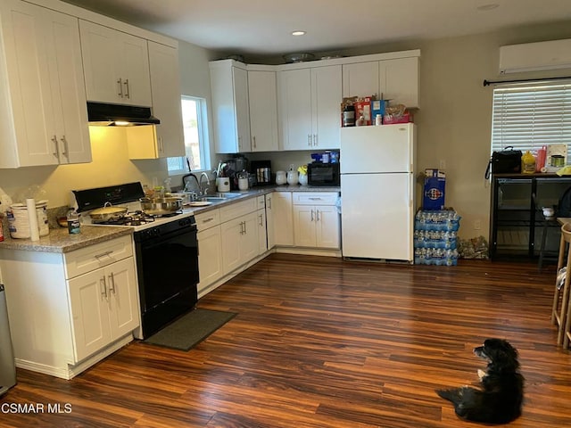 kitchen featuring white fridge, a wall unit AC, black gas stove, white cabinetry, and dark hardwood / wood-style flooring