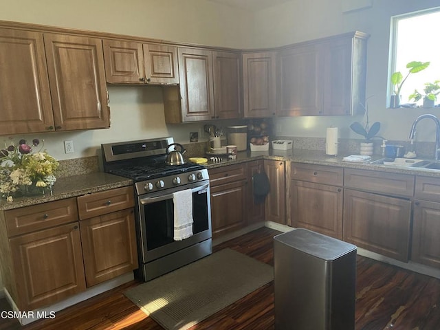 kitchen with dark wood-type flooring, sink, stone countertops, and stainless steel gas range oven