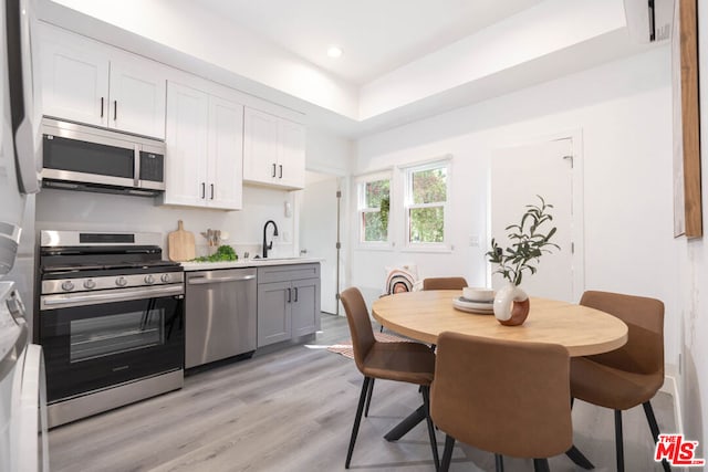 kitchen with sink, light hardwood / wood-style floors, white cabinets, and appliances with stainless steel finishes