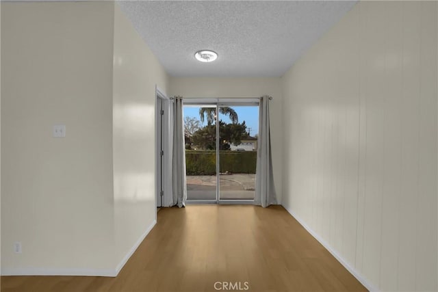 corridor featuring wood-type flooring and a textured ceiling