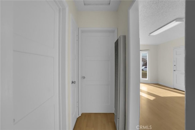 hall with a textured ceiling and light hardwood / wood-style floors