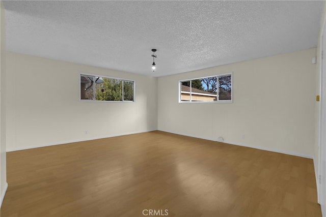 empty room featuring a textured ceiling and hardwood / wood-style flooring