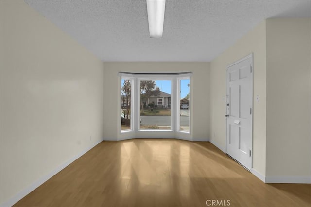 spare room featuring a textured ceiling and light hardwood / wood-style floors