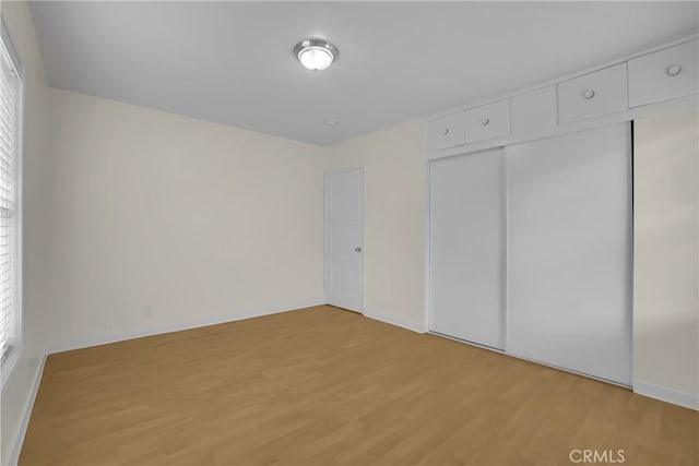 unfurnished bedroom with light wood-type flooring and a closet