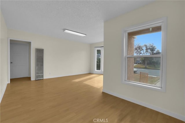 unfurnished room with a textured ceiling and wood-type flooring