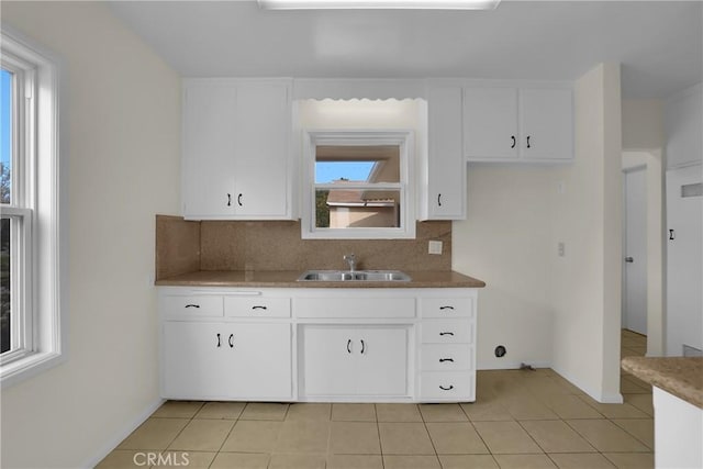 kitchen featuring sink, white cabinetry, light tile patterned floors, and tasteful backsplash