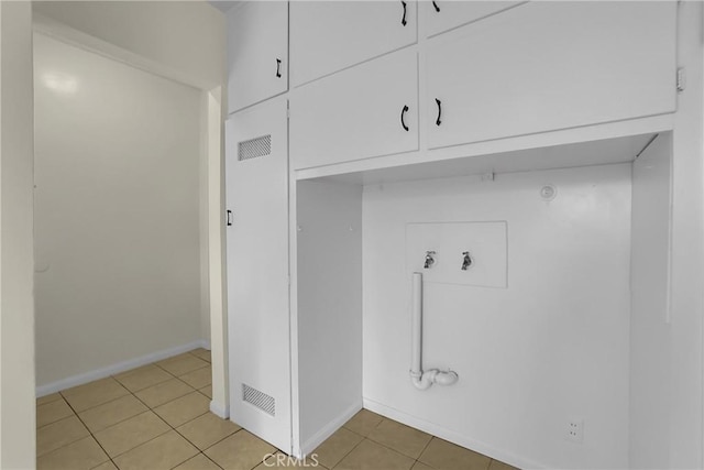 laundry area featuring hookup for a gas dryer, light tile patterned floors, hookup for a washing machine, and cabinets