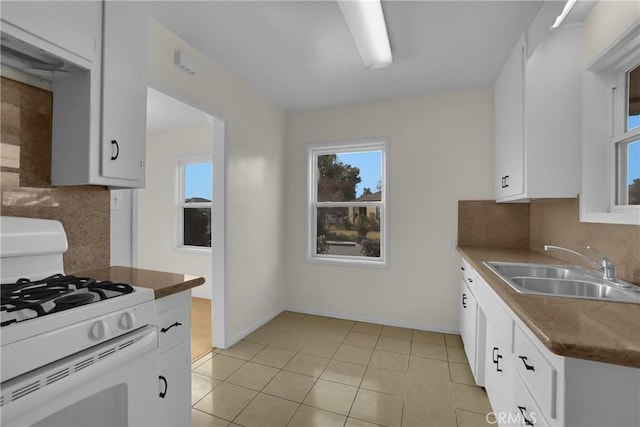 kitchen featuring white cabinets, decorative backsplash, sink, white gas stove, and light tile patterned floors