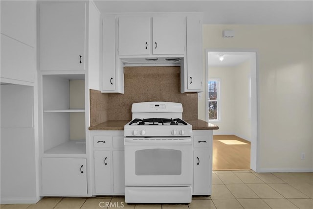 kitchen with tasteful backsplash, white cabinets, white gas range oven, and light tile patterned flooring