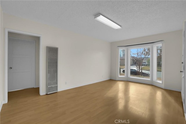 empty room with light hardwood / wood-style floors and a textured ceiling