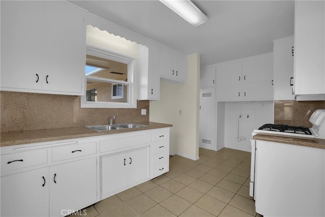 kitchen featuring white cabinetry, tasteful backsplash, sink, white gas stove, and light tile patterned flooring