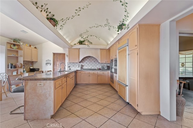 kitchen with kitchen peninsula, vaulted ceiling, sink, and light brown cabinets