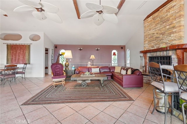 tiled living room with ceiling fan, lofted ceiling, and a stone fireplace