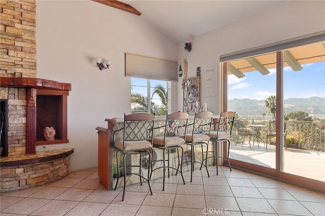 tiled dining room with lofted ceiling, a fireplace, and a mountain view