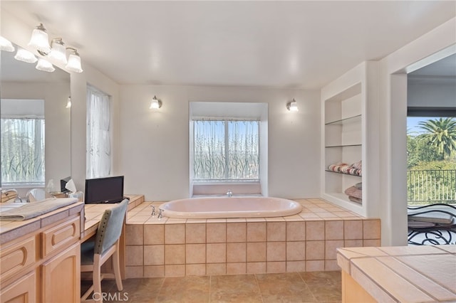 bathroom featuring built in shelves, tile patterned floors, vanity, and tiled tub