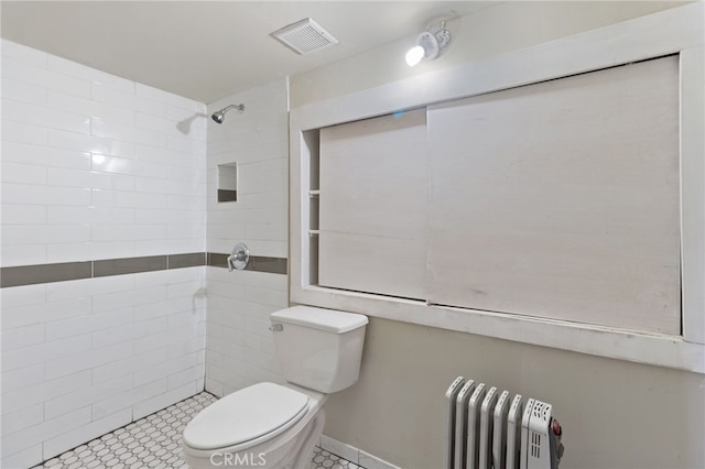 bathroom featuring toilet, radiator, and tiled shower