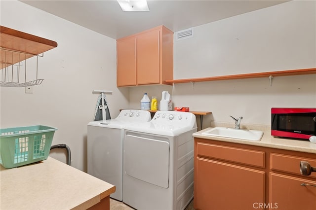 clothes washing area featuring washer and clothes dryer, sink, and cabinets