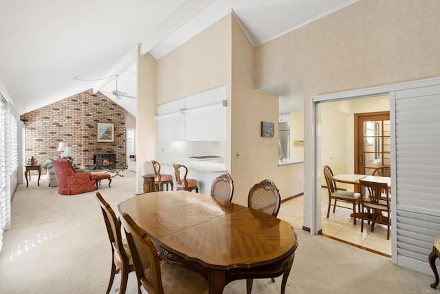 carpeted dining area with ceiling fan, a wealth of natural light, lofted ceiling with beams, and a fireplace