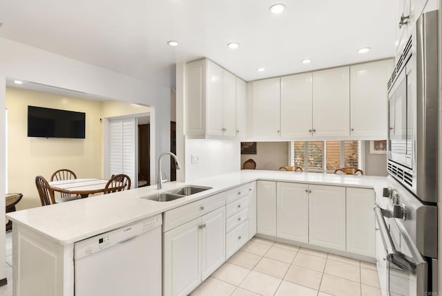 kitchen featuring white cabinetry, white dishwasher, kitchen peninsula, and sink