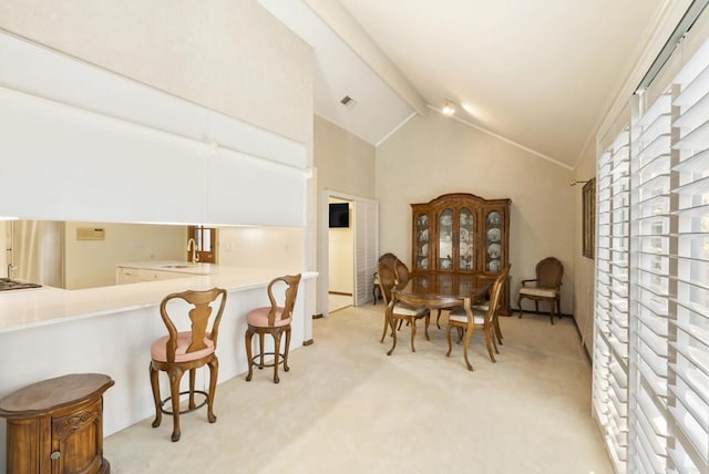 interior space with sink, light carpet, and vaulted ceiling with beams