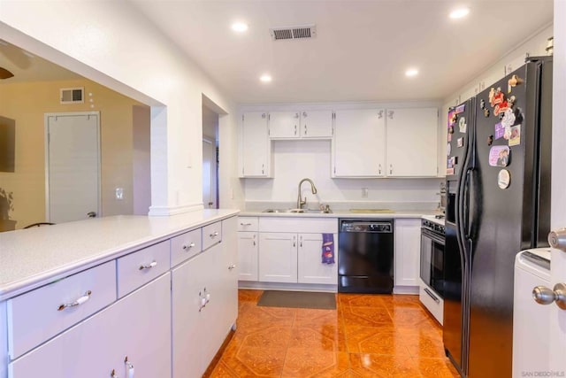 kitchen featuring white cabinets, black appliances, washer / dryer, sink, and light tile patterned floors