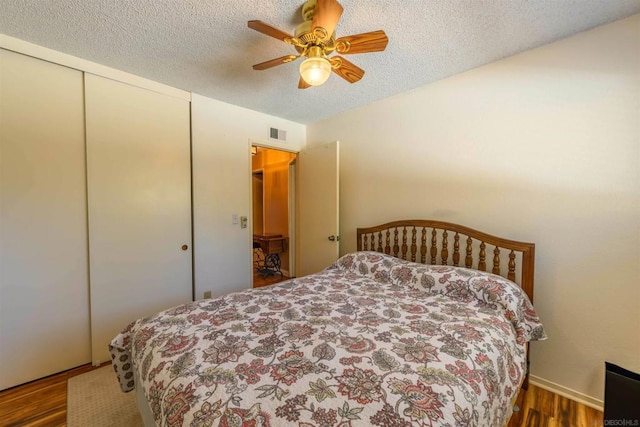 bedroom featuring a textured ceiling, ceiling fan, dark hardwood / wood-style flooring, and a closet