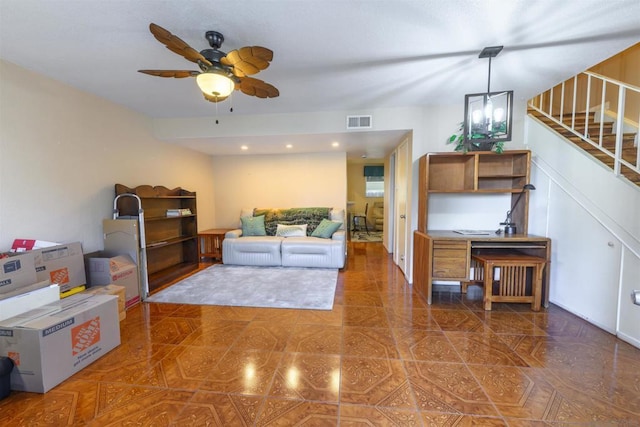 living room with ceiling fan with notable chandelier and dark tile patterned floors