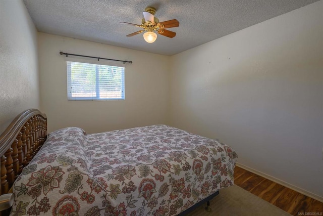 bedroom with ceiling fan, wood-type flooring, and a textured ceiling