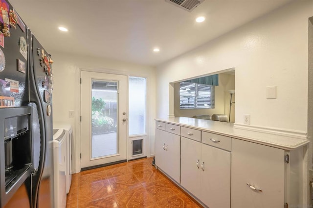 kitchen featuring washer and dryer and white cabinets