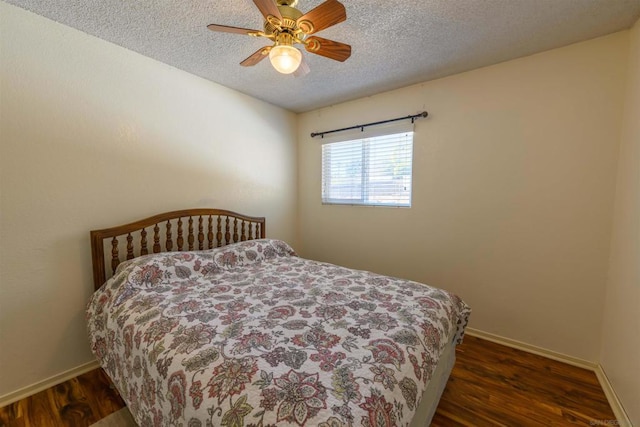 bedroom with ceiling fan, dark wood-type flooring, and a textured ceiling