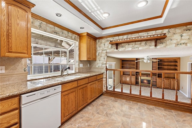 kitchen featuring white dishwasher, sink, a tray ceiling, and ornamental molding