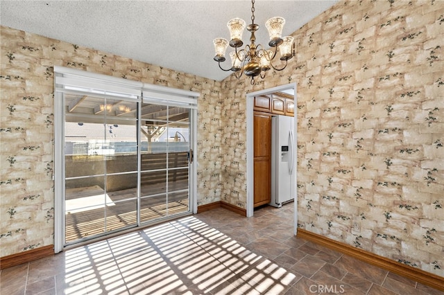 unfurnished dining area featuring an inviting chandelier and a textured ceiling