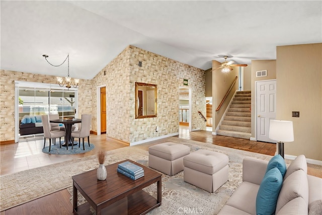 living room featuring ceiling fan with notable chandelier, lofted ceiling, and light hardwood / wood-style floors