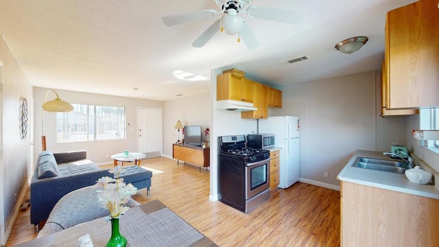 kitchen with sink, ceiling fan, stainless steel appliances, light brown cabinets, and light hardwood / wood-style flooring