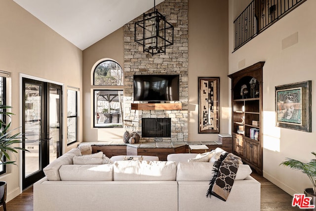 living room featuring high vaulted ceiling, dark hardwood / wood-style flooring, and a stone fireplace