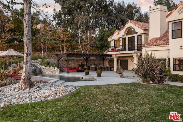 yard at dusk with a balcony, a pergola, an outdoor hangout area, and a patio