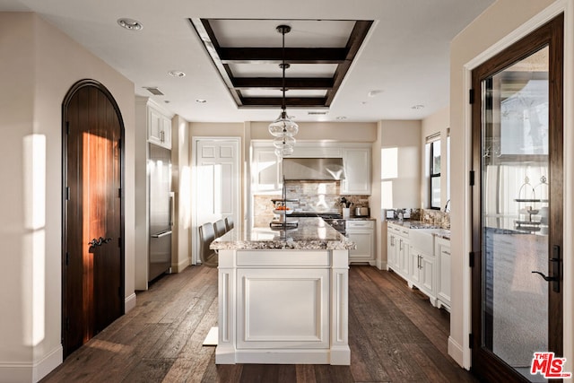 kitchen featuring pendant lighting, a center island, white cabinetry, dark hardwood / wood-style floors, and light stone counters