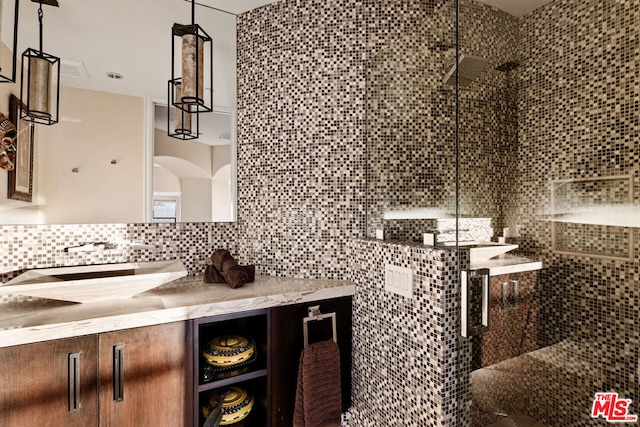 bathroom with vanity, decorative backsplash, and a tile shower