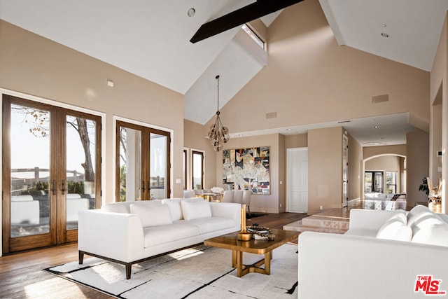 living room with high vaulted ceiling, french doors, and light wood-type flooring