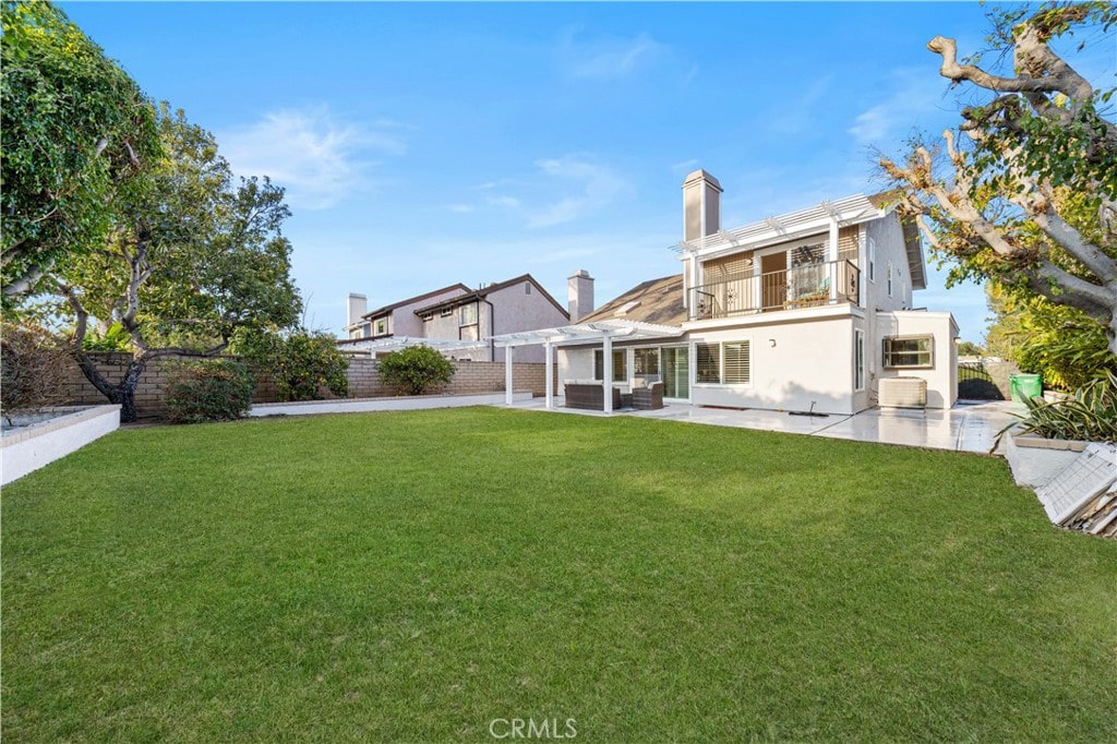 back of property featuring a pergola, a yard, a balcony, and a patio